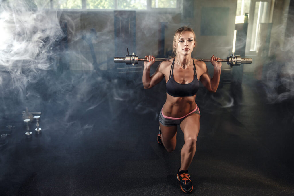 young-sexy-girl-in-the-gym-doing-squat-on-smoke-background